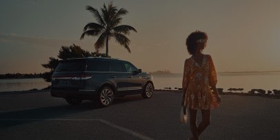 A woman standing in front of a parked Lincoln Navigator.